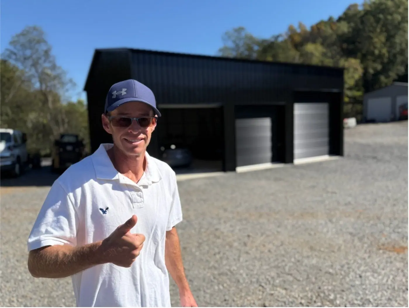 Nathan giving a thumbs up in front of a black metal garage